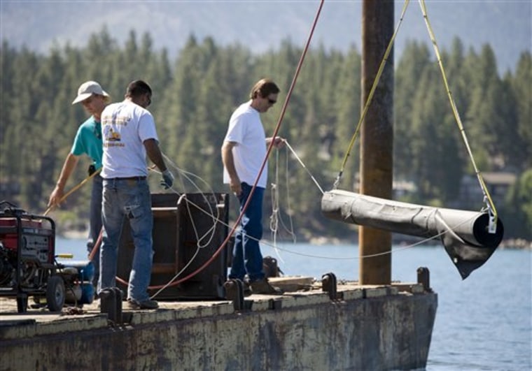 In this photo taken Friday, July 9, 2010, workers on a barge lower one of eight rubber rolls into 15-feet of water at Marla Bay near Zephyr Cove, Nev. Scuba-diving scientists are unrolling long rubber mats across the bottom of Lake Tahoe coves in an attempt to quell a clam invasion that could cloud the world-reknown cobalt waters. (AP Photo/The Sacramento Bee, Randy Pench) MAGS OUT; TV OUT; NO SALES; MANDATORY CREDIT